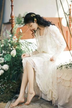 辛伊 一个穿着白色连衣裙的美丽年轻女子坐在有花卉遮阳伞的吊床床上